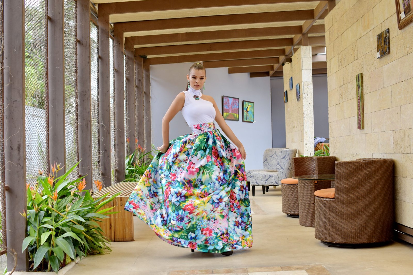 About Stylish woman in a floral skirt poses confidently indoors with elegant decor.